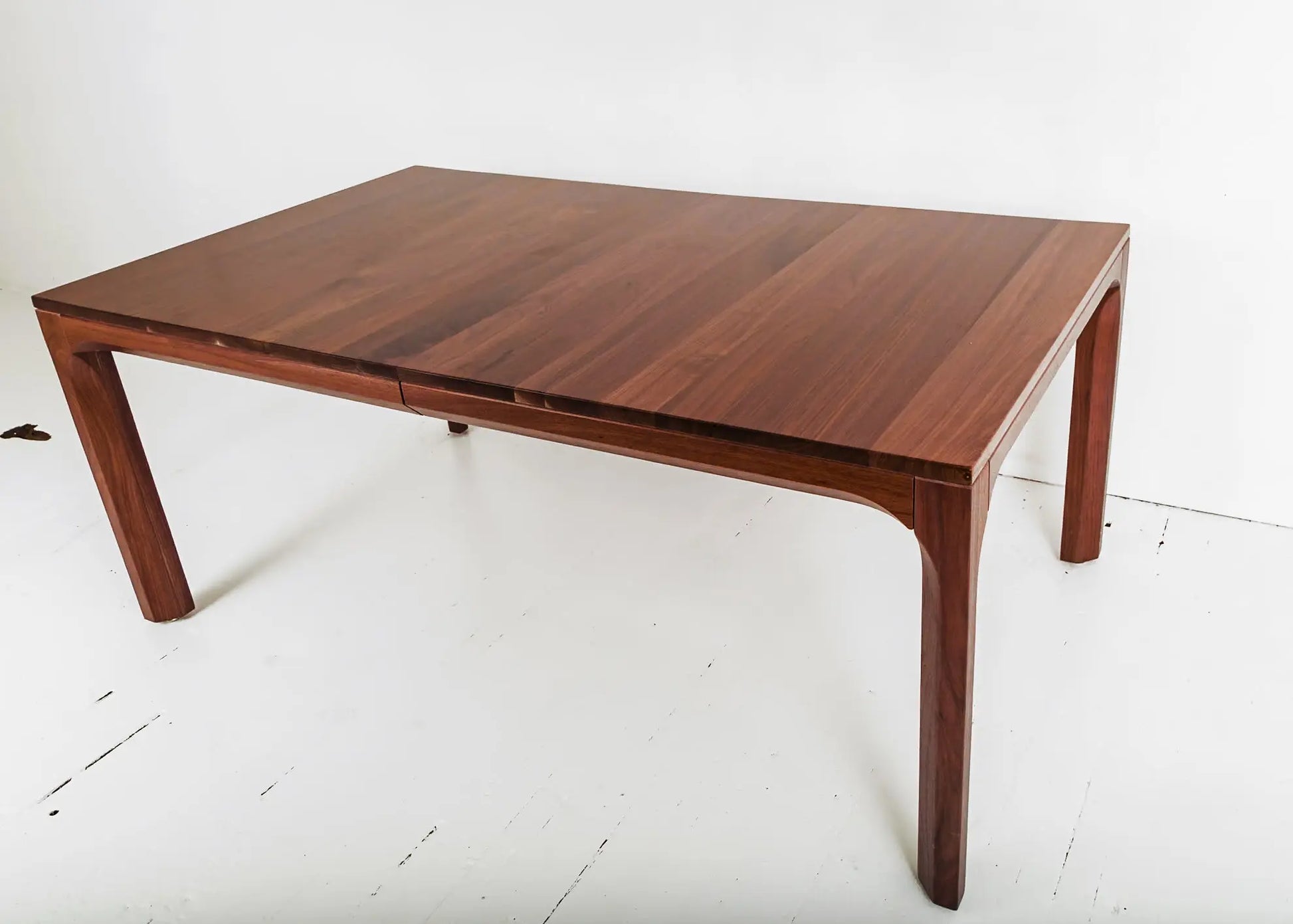 Walnut dining table in a bright minimalist room with orange accent chairs
