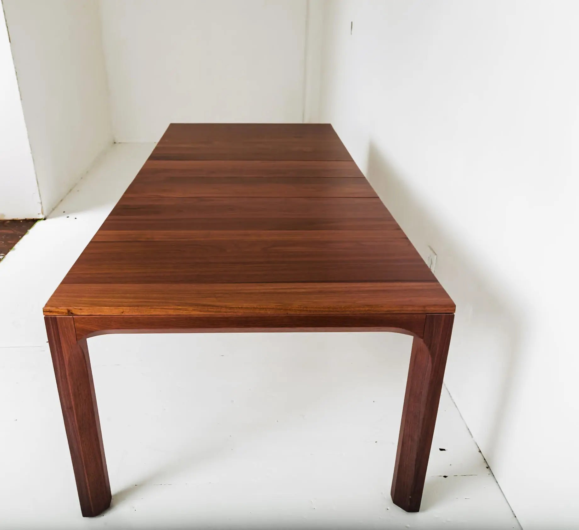 Walnut dining table with minimalist orange chairs in a contemporary room
