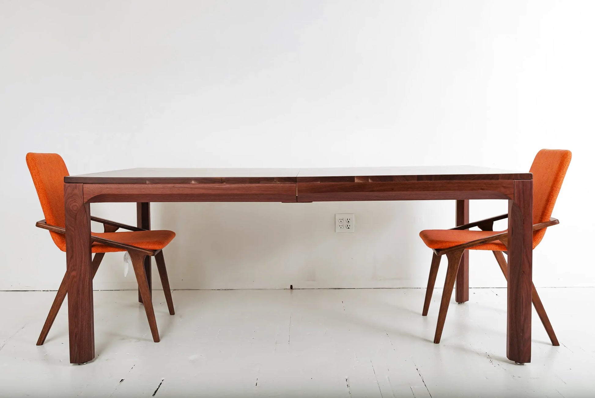 Modern walnut dining table setup with Scandinavian-inspired orange chairs
