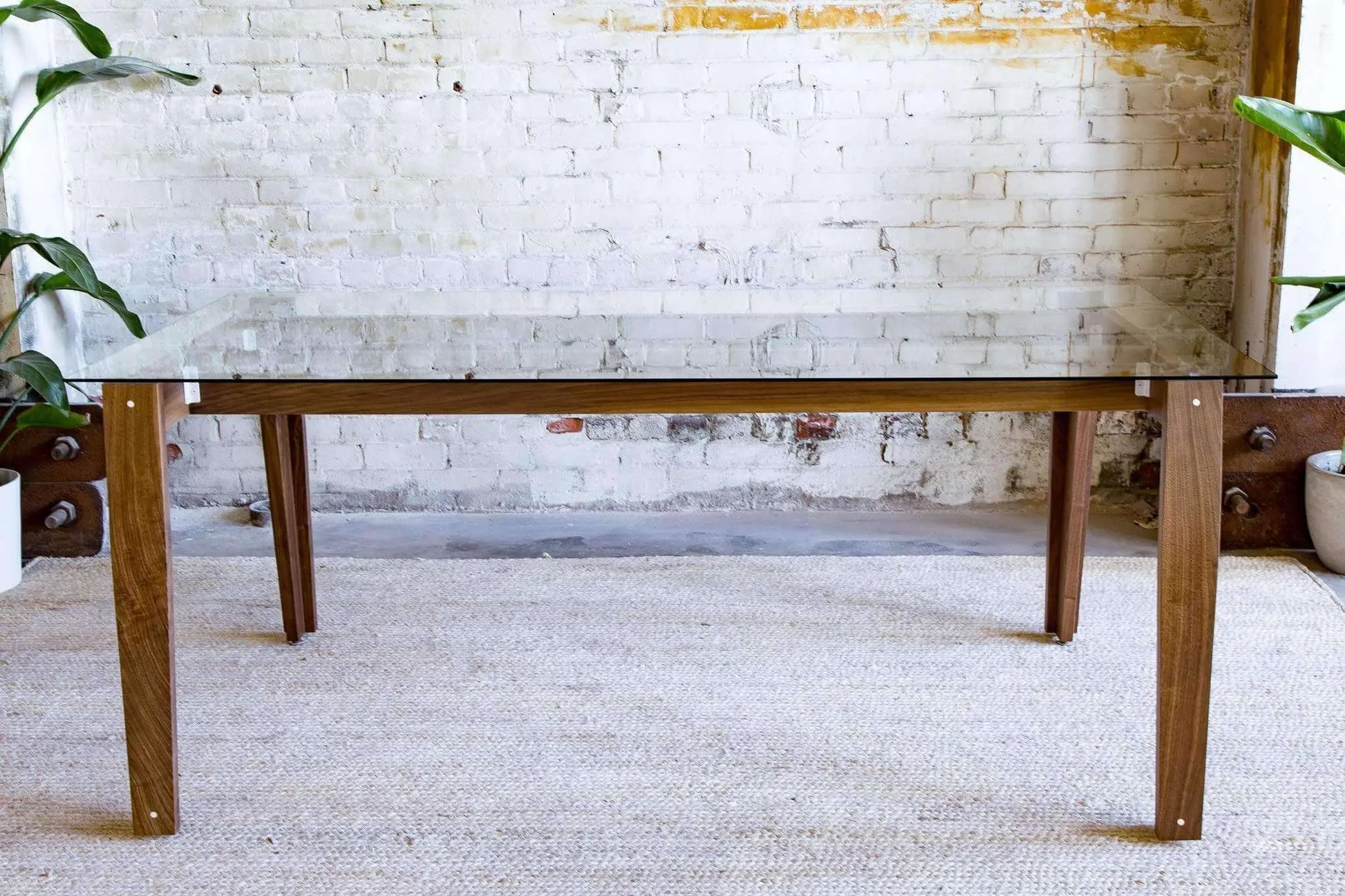 Sleek glass-top dining table with walnut-finished base for modern homes