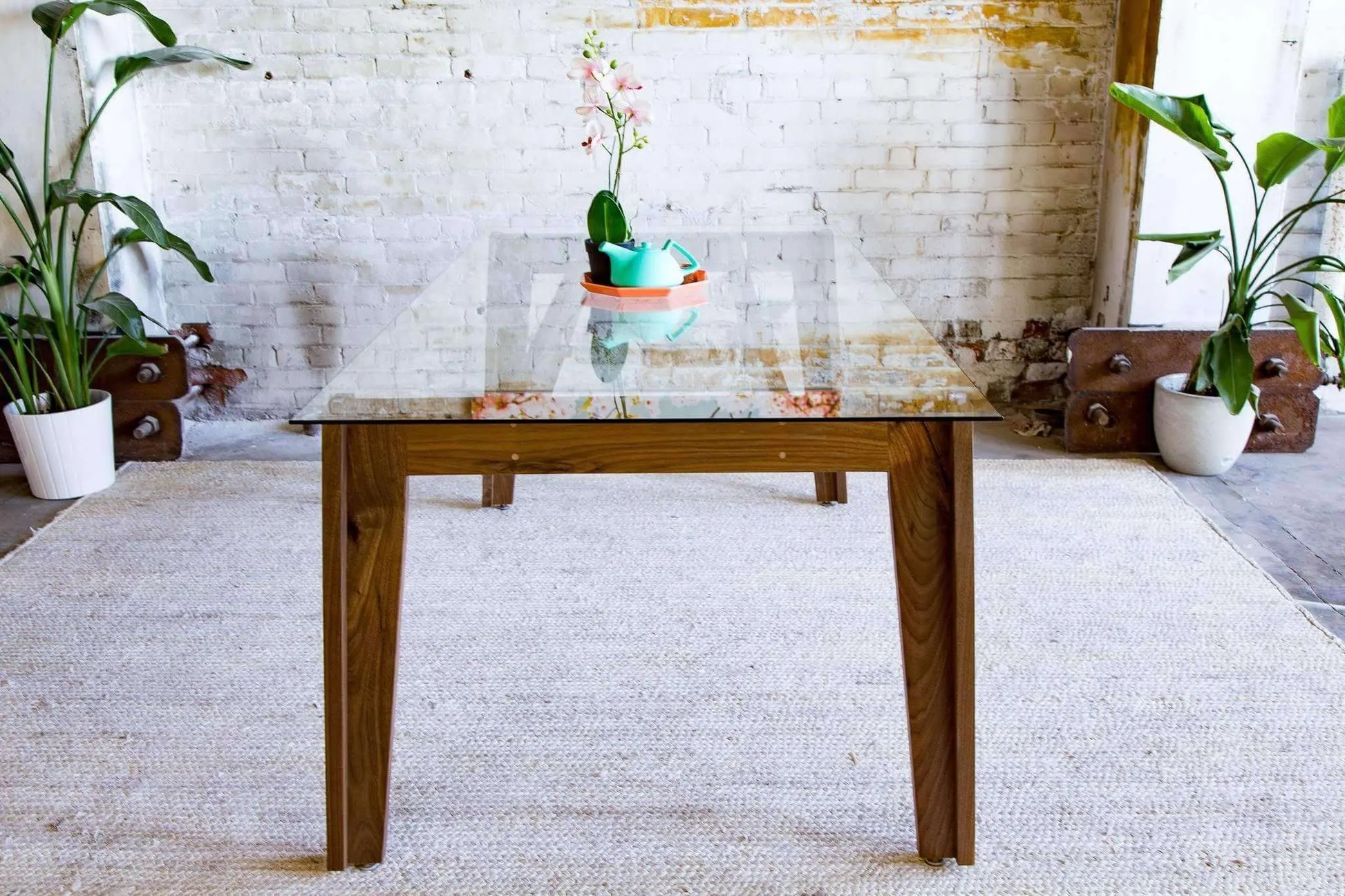 Clear glass-top dining table with angled wooden support legs